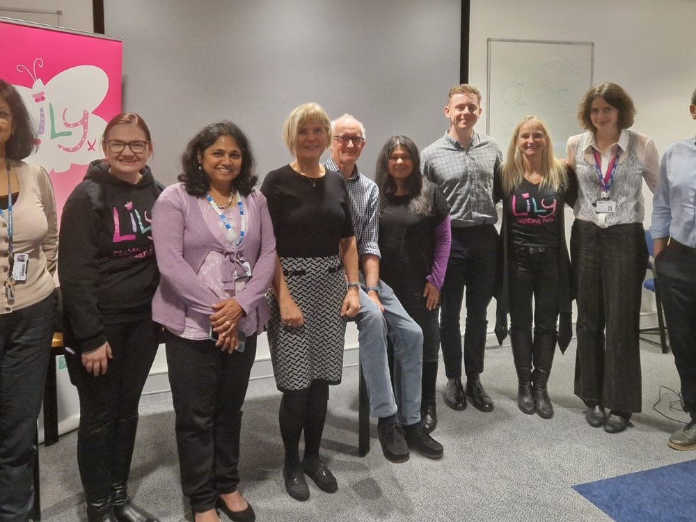 A group of people lined up standing in front of a Lily-branded banner