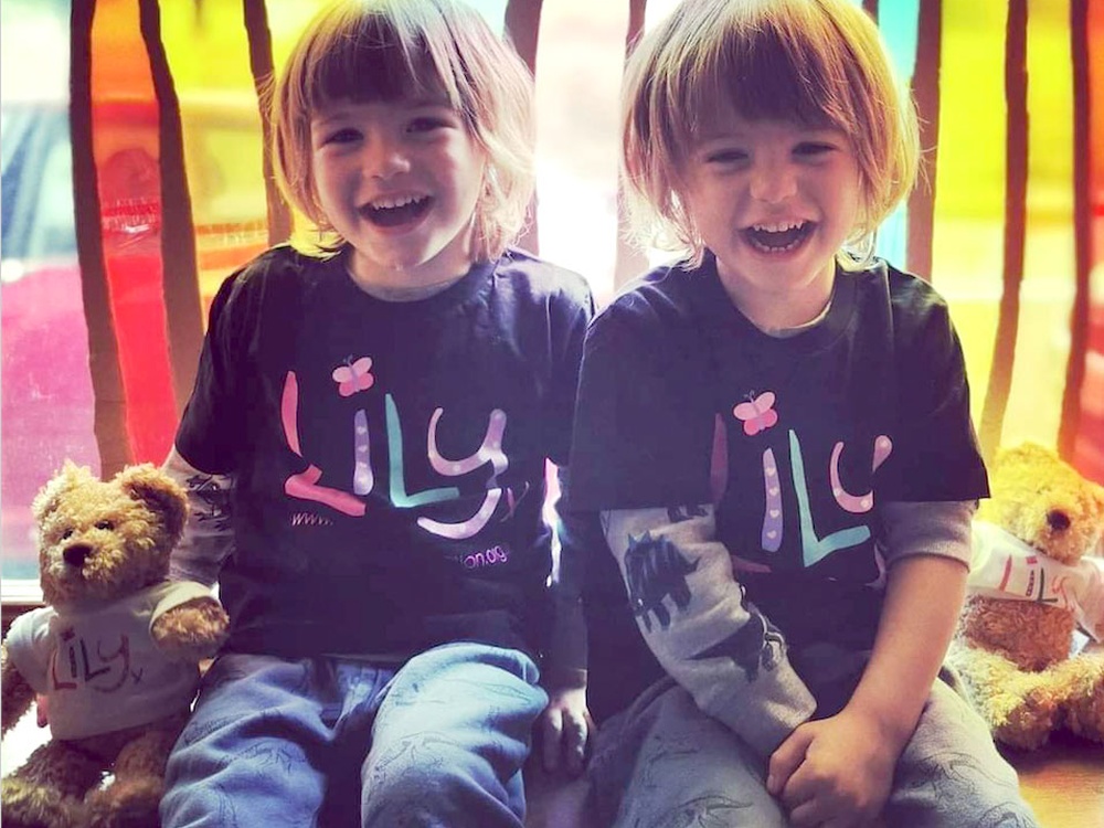 Two little boys sitting next to each other smiling and wearing Lily Foundation Tshirts