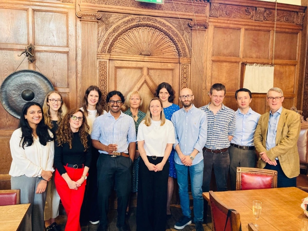 A group of people standing together in front of a panelled wall