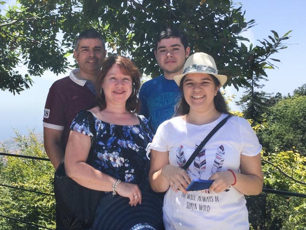 A man and a boy stand behind a women and a girl. All are smiling at the camera