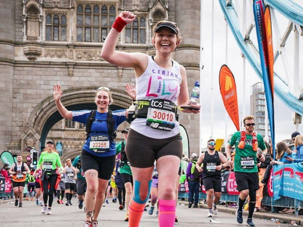 A woman in a Lily Foundation top fist-pumping and smiling whilst running the London Marathon