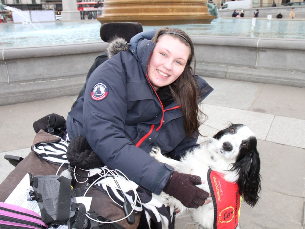 A woman in a wheelchair petting a dog