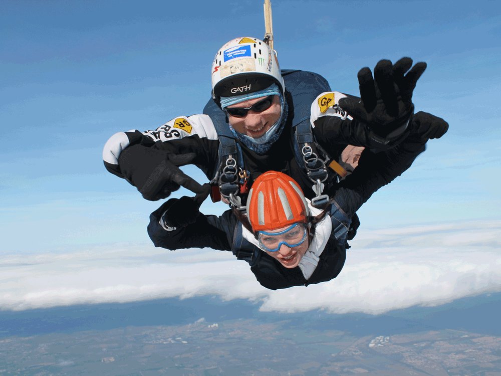 Two people tandom sky diving with their arms out