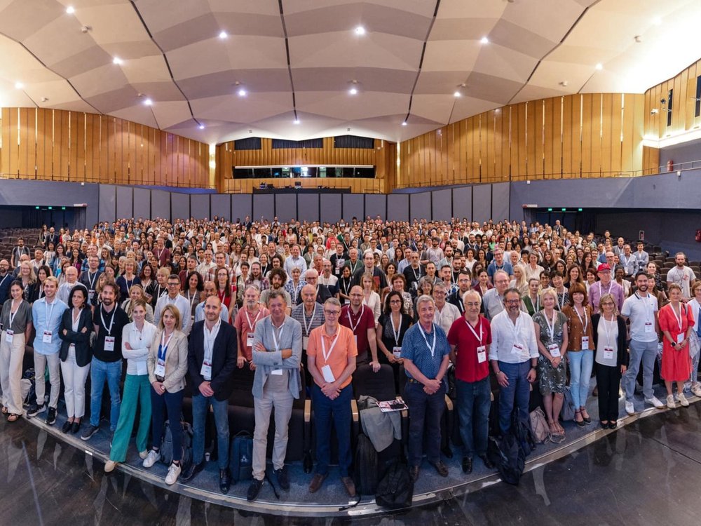 Large group of people standing together in a room at a conference