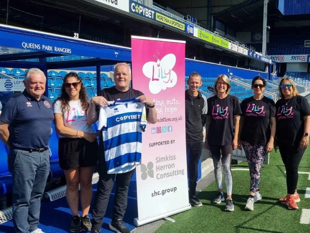 A group of people standing with Kevin pitchside at QPR