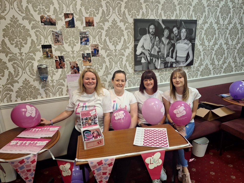 Four women wearing Lily tops surrounded by balloons and leaflets