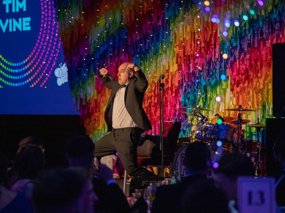 Comedian Tim Vine speaking on stage at the Lily ball