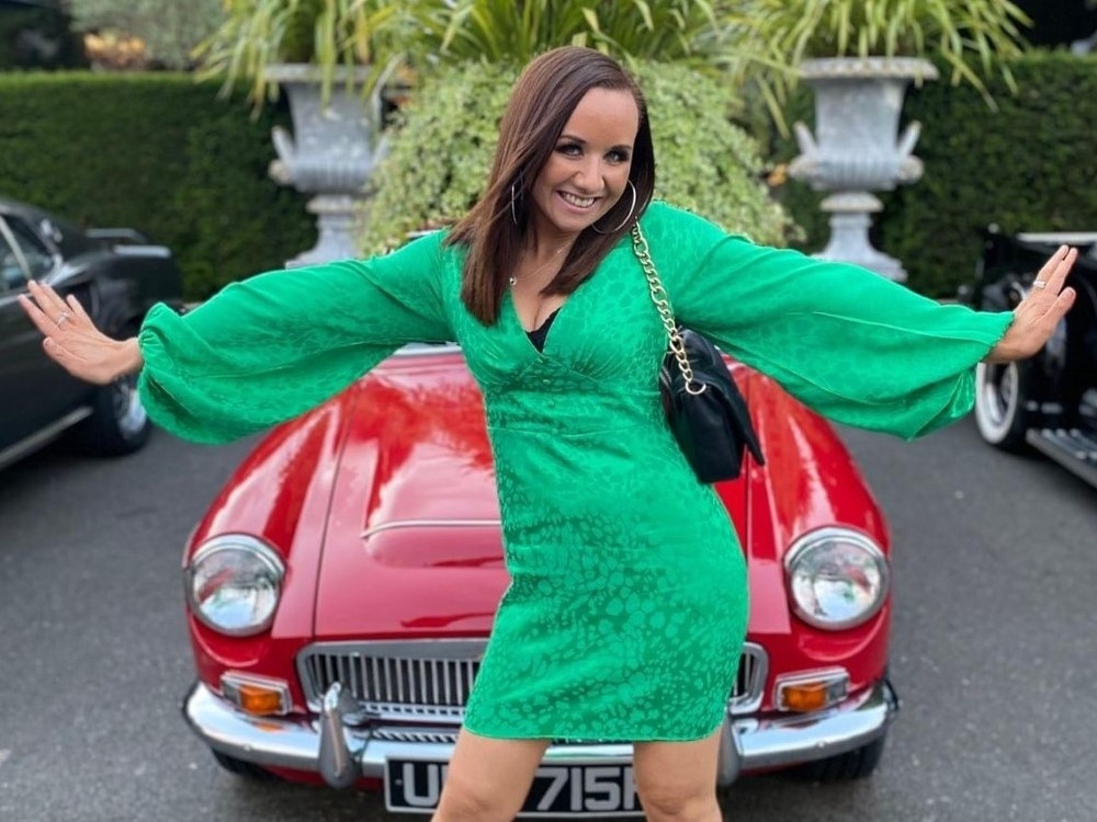 A young adult mito warrior in a green dress posing in front of a red vintage car