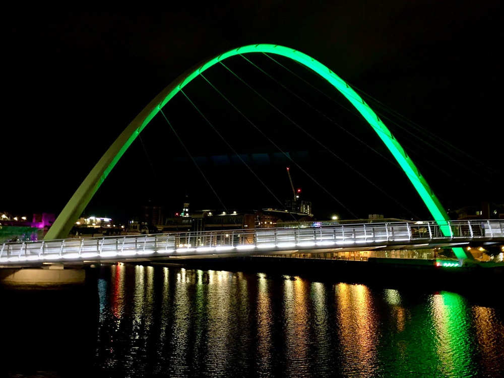 Gateshead Millennium bridge lit up green against the night sky