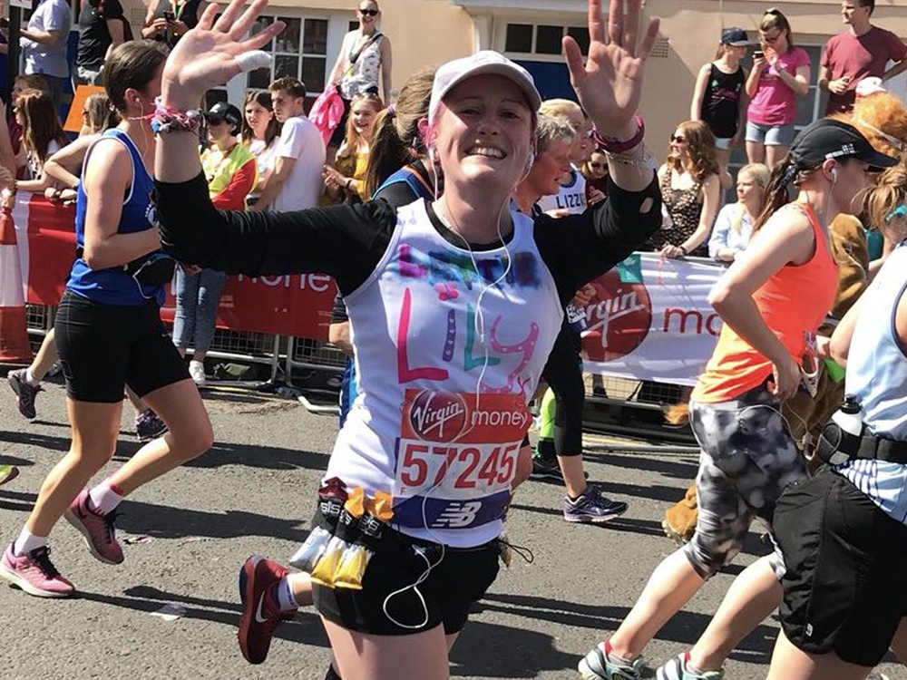 A woman in a Lily top running and raising her arms in the air