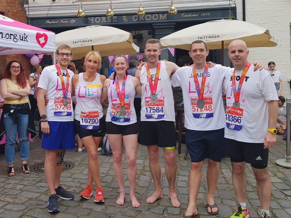 A group of runners in Lily tops with their arms around each other