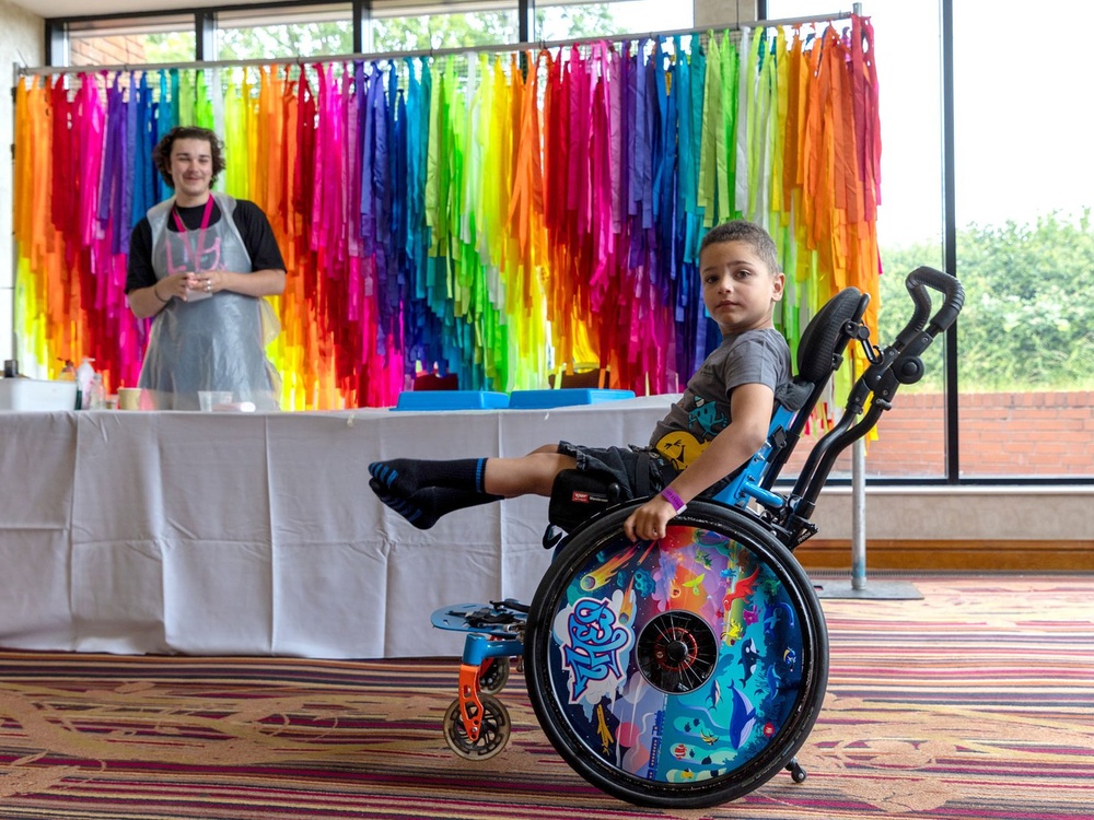 A mito warrior in a wheelchair in front of a table with crafting equipment on