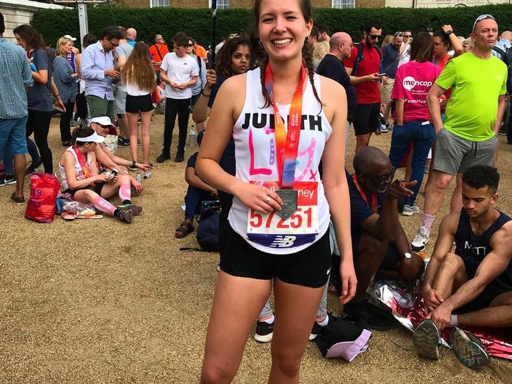 A woman standing in a Lily top wearing her London marathon finishers medal