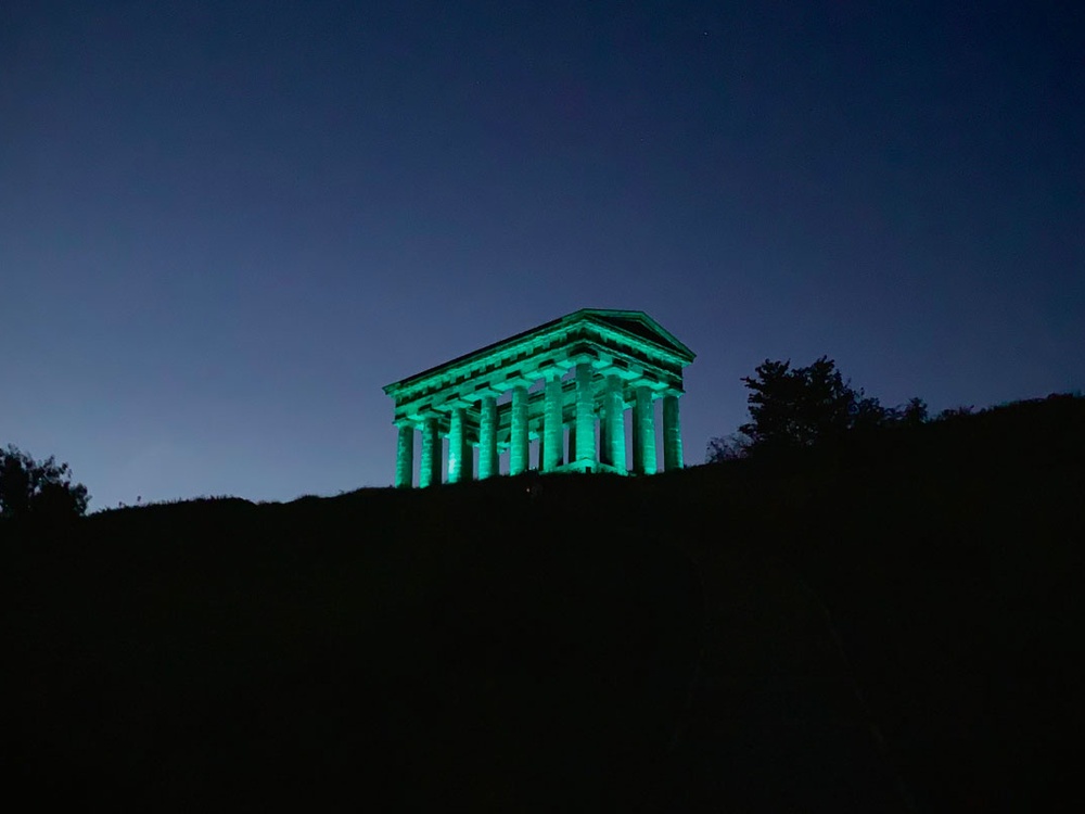 Penshaw Monument lit up green against the dark sky