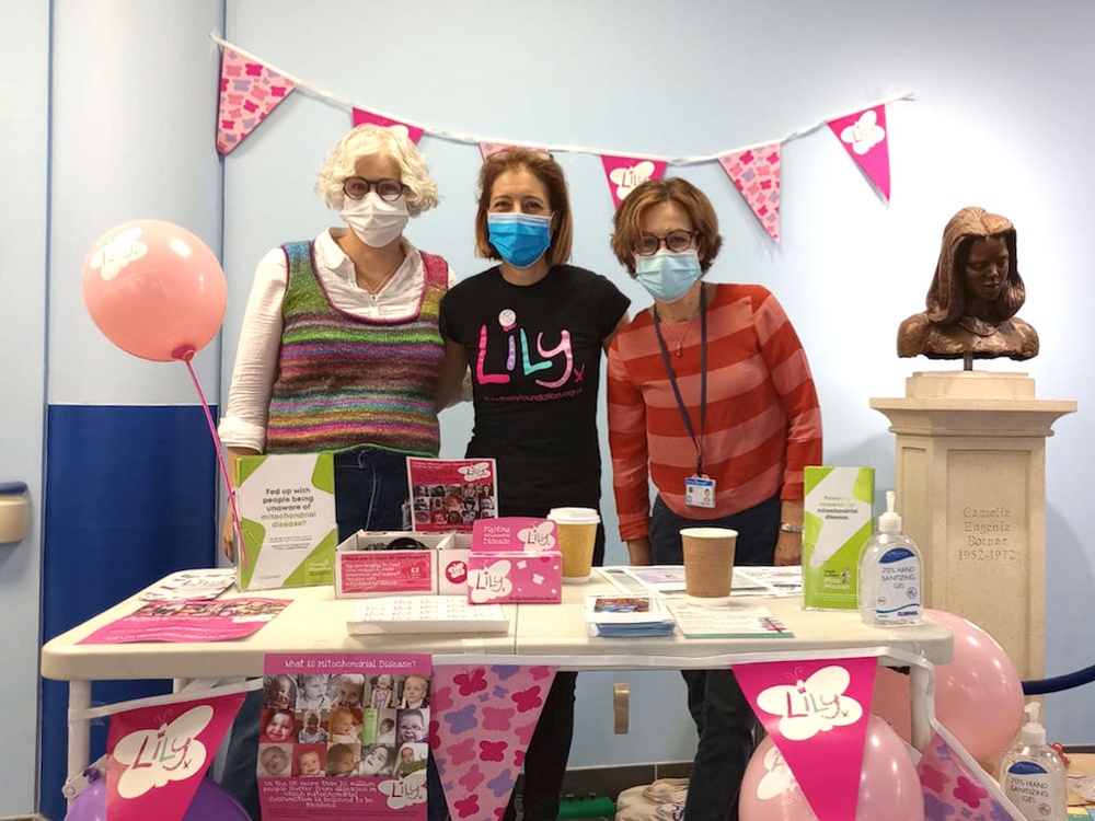 Three people standing behind a Lily Foundation awareness stand with bunting and leaflets