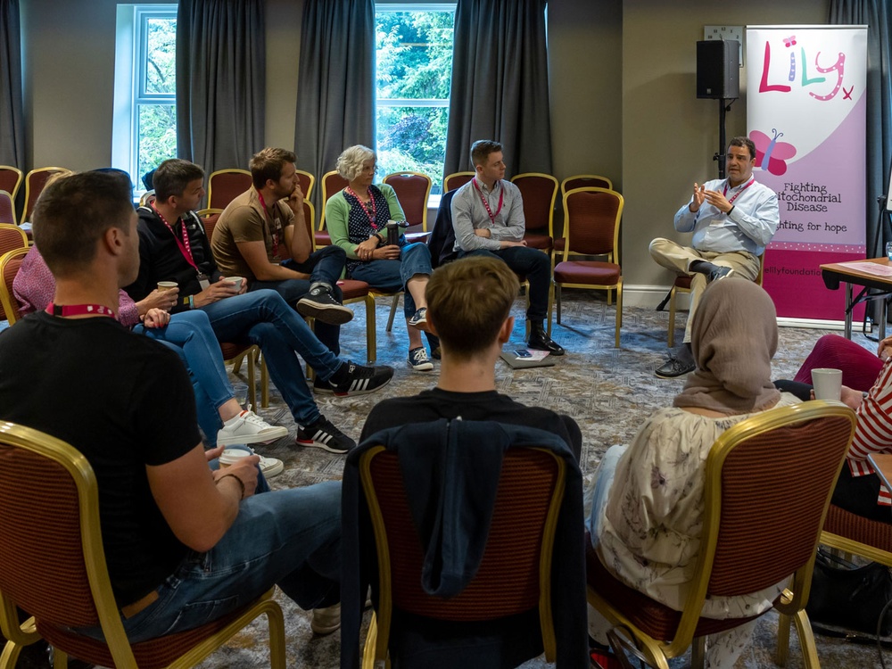 A group of people sitting in a circle listening to a man speaking