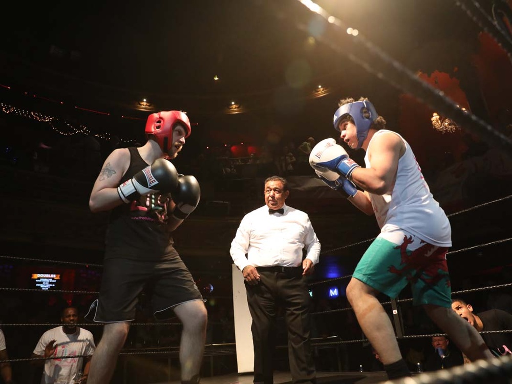 Two boxers sparring in the ring with the referee watching