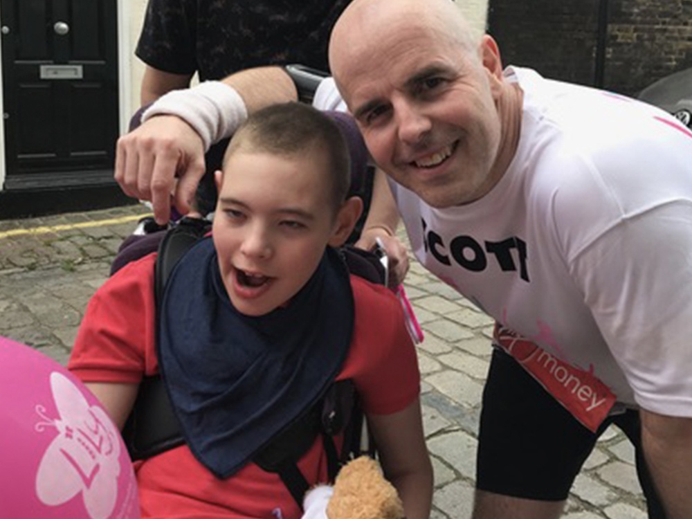 A man leaning down and smiling with his arm around a young boy in a buggy