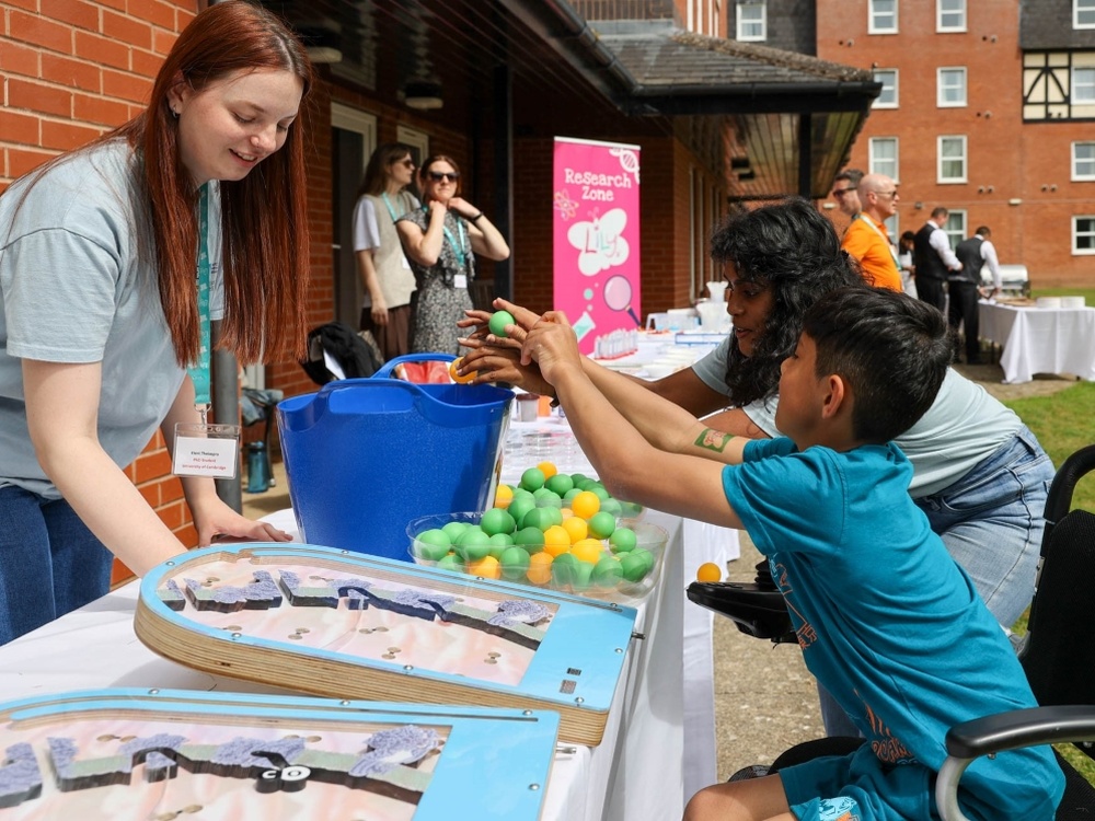 A young boy in a wheelchair leans forward to take part in an activity at a table