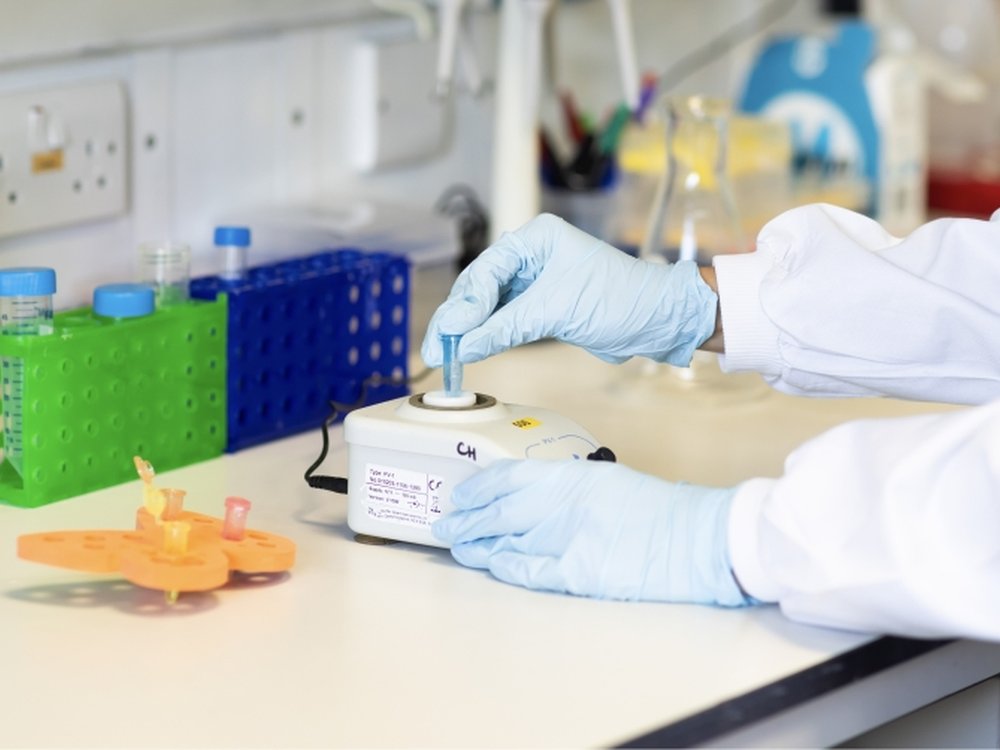 Lily at centre of exciting new mito research project - Someone in a lab coat and protective gloves standing at a bench in a science lab