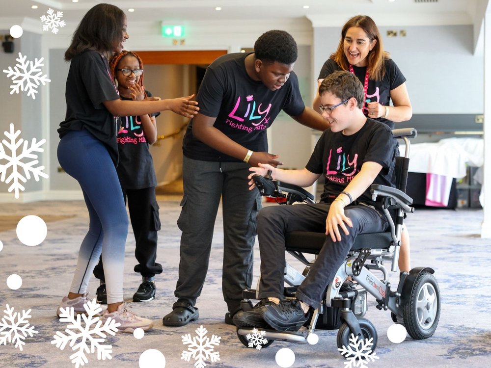 Double your Christmas donation today! - Young mito patient in a wheelchair surrounded by people at the Lily support weekend